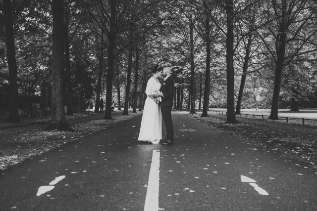 Frisch verheiratetes Paar geht nach einer kleinen standesamtlichen Trauung Hand in Hand über eine Promenade.
